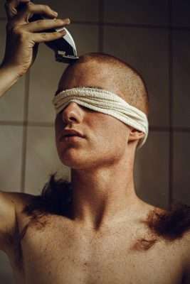 blindfolded man shaving head